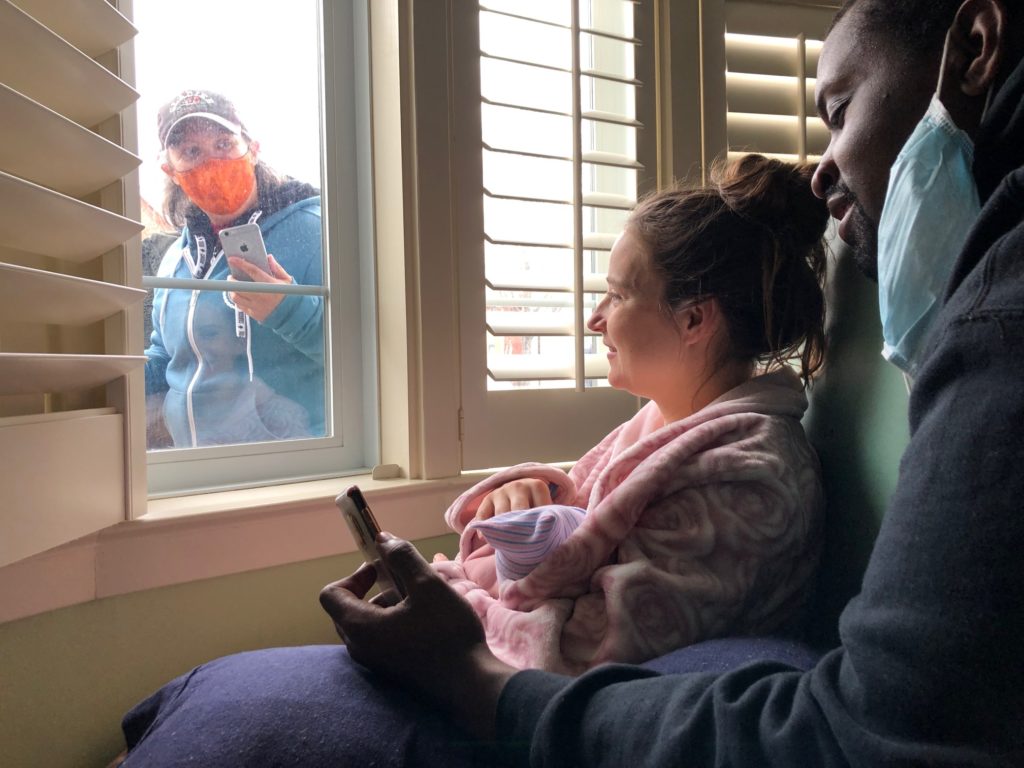 parents introduce new baby to family through birth center window